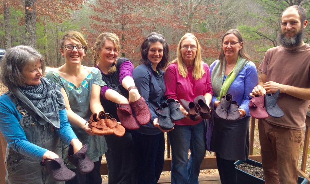 A group photo of smiling shoemaking students at Brasstown showing off their work