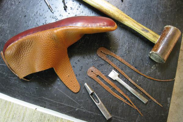 Handmade turn shoe in progress on workbench with tools and materials nearby