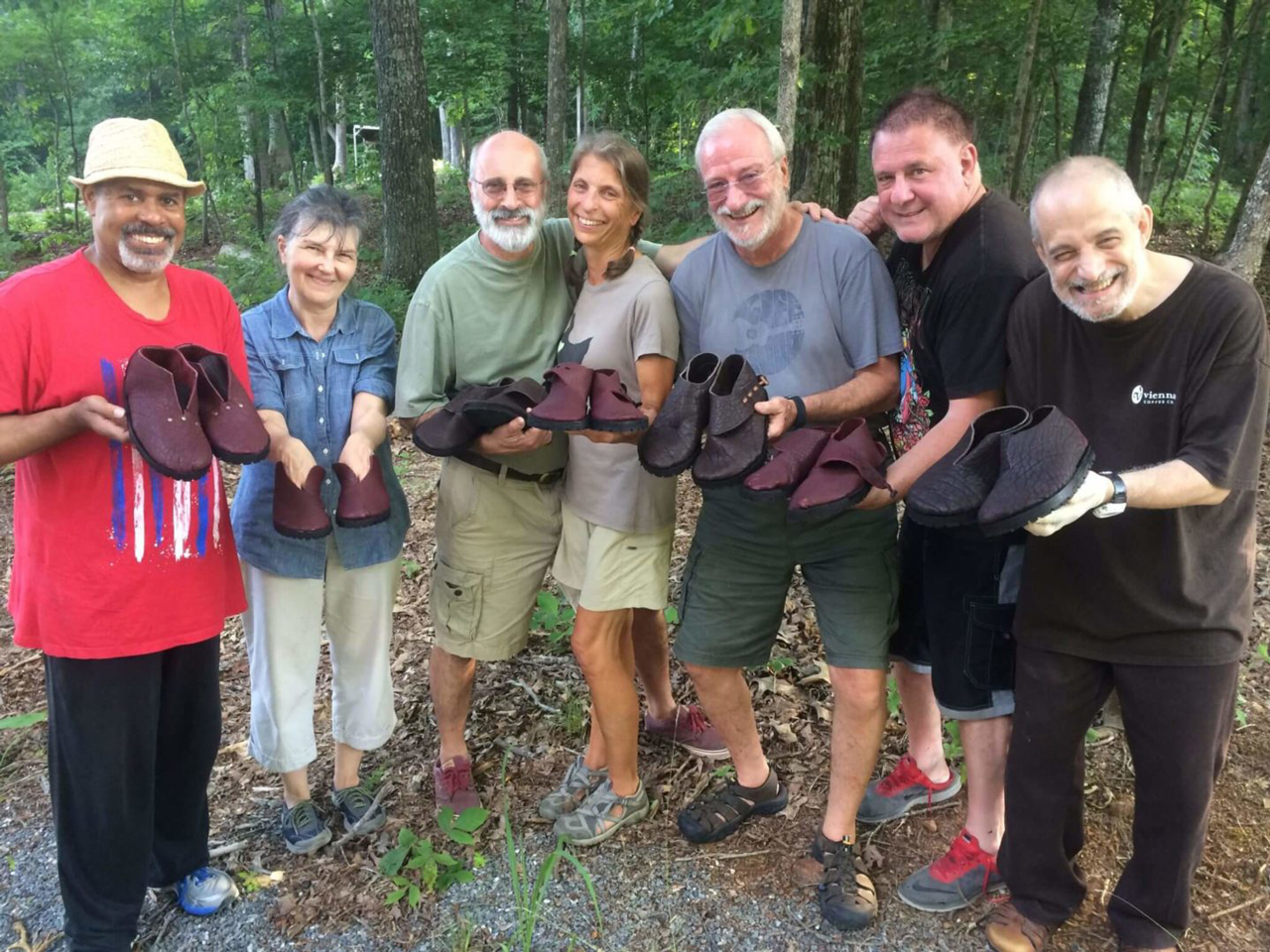 A diverse group of students in the woods near Appomattax, Virginia pose with their new handmade shoes