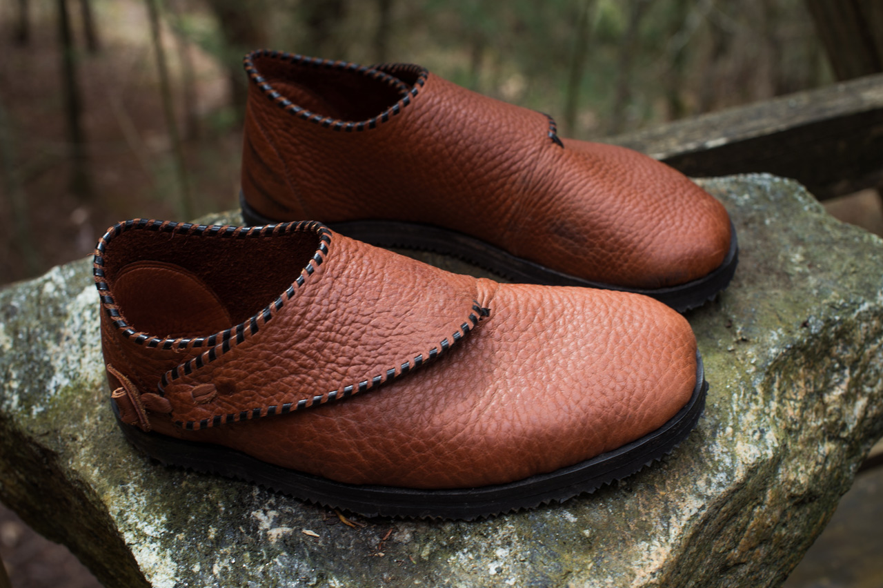 A fine pair of handmade loafers made at shoemaking class displayed on a mossy rock